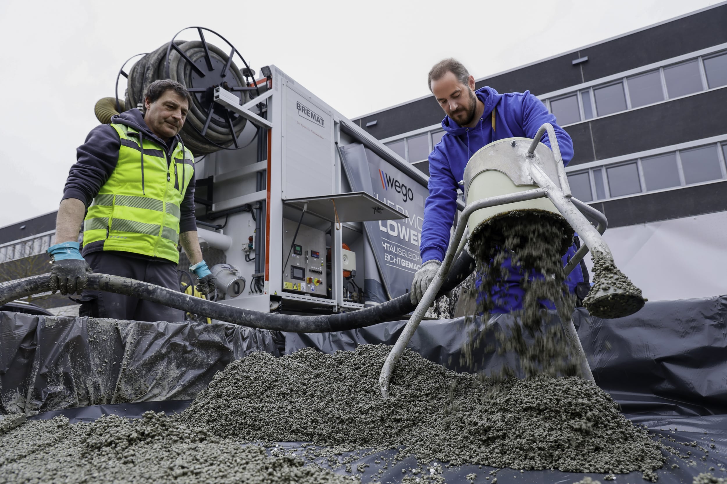 Im Hintergrund steht der wego vti Thermoblower und im Vordergrund arbeiten zwei Männer am Leichtausgleich.