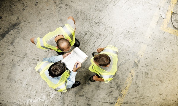 Directly above shot of supervisor discussing over documents with workers in warehouse